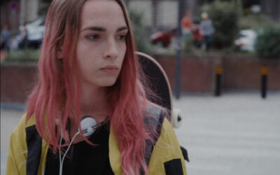 La chica de cabello rosa y una patineta al hombro